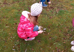 Zuzia i Oliwier szukają skarbów przy pomocy lup.